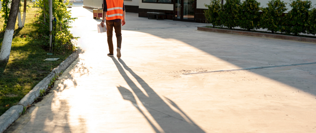 a man in a vest walking on a sidewalk